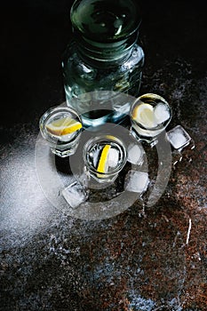 Vodka. Shots, glasses with vodka and lemon with ice .Dark stone background. Vertical image.