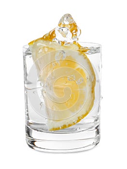 Vodka splashing out of shot glass with lemon on white background