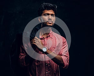 Vogue, fashion, style. Handsome young Indian guy wearing a pink shirt holding a jacket on his shoulder and looking