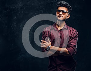 Vogue, fashion, style. Handsome young Indian guy wearing a stylish shirt and sunglasses posing with crossed arms.