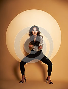 Vogue style portrait of beautiful woman posing in studio in the spoatlight