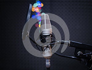 Voice microphone with shock mount and pop filter on professional tripod in audio recording vocal studio. Concept of