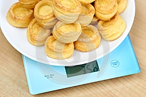 A vol-au-vent dish lies on the blue scales. Calorie counting concept, figure tracking