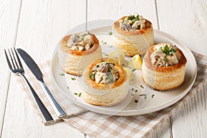 Vol-au-Vent is a hollow puff pastry shell filled with a creamy mushroom and chicken filling closeup on the plate. Horizontal