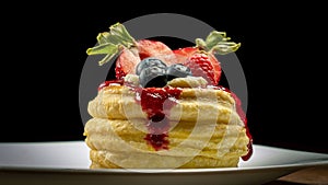 Vol-au-vent puff pastry decorated with fresh strawberries, blueberries and dripping berry coulis on white plate. Close-up