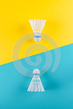 Volant and racket, badminton on yellow, blue background. Concept excitement, resistance, competition. Pop Art