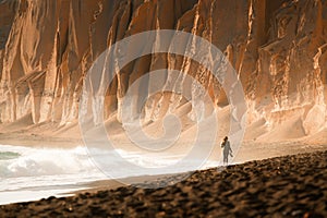 Volcanic cliffs on Vlichada beach in Santorini island, Greece. Woman walking along the beach