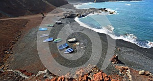 Volcanic  Coastline Rocks and Waves at El Golfo Lanzarote Spain with boats on beach.