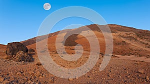 The volcanic cone of Pico del Teide in the early morning at sunrise with the full moon.