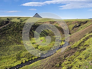 Volcanic landscape of green Storasula mountain with lush moss and blue creek water between Emstrur and Alftavatn camping