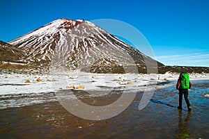 Volcanic landscape of Mount Ngauruhoe, traveler and tramper caring backpack walking to the volcano