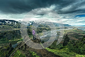 Volcanic landscape of Valahnukur trail and hiker woman standing in Thorsmork valley and moody sky in summer at Iceland