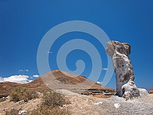 Volcanic red hillsides and wind erosion artifacts on the background of deep blue sky with white clouds. Lanzarote