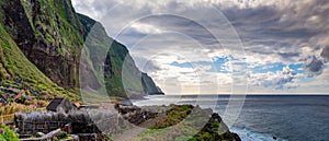 Volcanic rock cliffs Achadas da Cruz in sunlight. Sunset seascape of Madeira