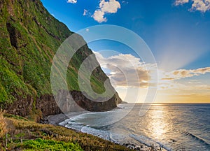 Volcanic rock cliffs Achadas da Cruz in sunlight. Sunset seascape of Madeira