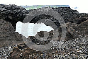 Volcanic rockbridge above a tunnel at the coast of Island