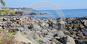 Volcanic stones on the seashore, great volcanic rocks on the Ionian sea, seashore, palm trees on the seashore