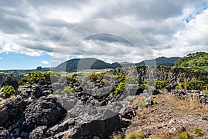 Volcanic stones and shrubs with mountains in the background at the Natural Reserve of Alagoa da FajÃÂ£zinha, Terceira - Azores photo