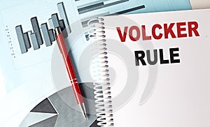 VOLCKER RULE text on a notebook with pen on a chart background