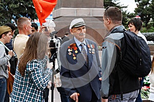 People interview a veteran of world war II on the Square of the Fallen Fighters in Volgograd