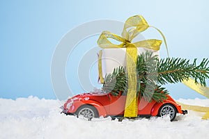 Volgograd, Russia - October 15, 2021: Small red retro toy car with a gift box with a gold ribbon and a Christmas tree on