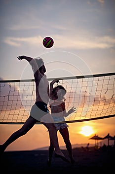 Volleyball at the beach. Friends playing game together. Man jumping and hitting ball. Sport, recreation, fun, togetherness,