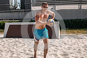 Volleyball beach male player getting ready to serve the ball on the beach court.