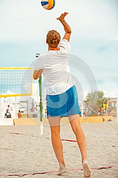 Volleyball beach player is a male athlete volleyball player getting ready to serve the ball on the beach.