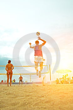 Volleyball beach player is a male athlete volleyball player getting ready to serve the ball on the beach and girl making