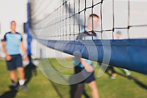 Volleyball game, junior teenage school team of kids play volleyball, players on the outdoor playground with net and green lawn