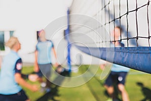 Volleyball game, junior teenage school team of kids play volleyball, players on the outdoor playground with net and green lawn