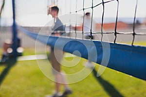 Volleyball game, junior teenage school team of kids play volleyball, players on the outdoor playground with net and green lawn