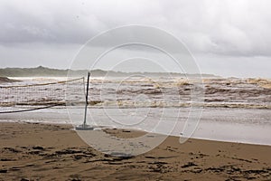A volleyball net stands abandoned as Tropical Storm Nate turns the waters of the Pacific red from storm run off. photo