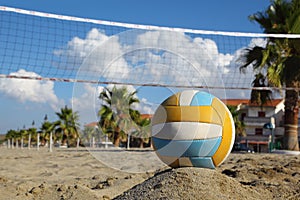 Volleyball net, volleyball on beach and palm trees