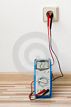 Voltage measuring with digital multimeter instrument on wall socket