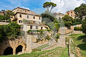 Volterra cityscape inside city walls, vintage houses on a hill surounded by pine and cypress trees, Tuscany