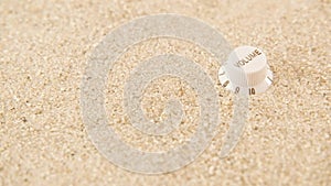 Volume knob isolated on bright sand rotating