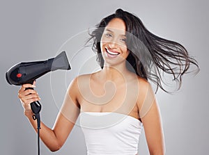 Volume and shine, thats all I want for my hair. Cropped portrait of an attractive young woman blowdrying her hair