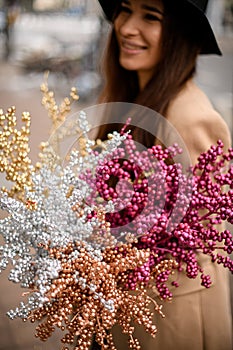 Voluminous bouquet in the hands of a girl in a black hat standing on a street