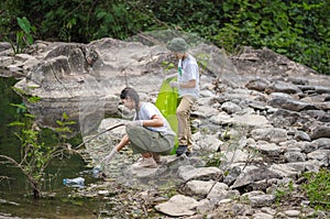 Volunteer Asian and children are collecting plastic bottles that flow through the stream into garbage bags to reduce global