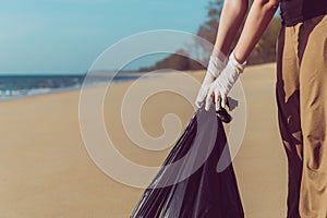 Volunteer asian woman holding black color garbage bag with keeping plastic bottle at the beach,Dispose recycle and waste managemen