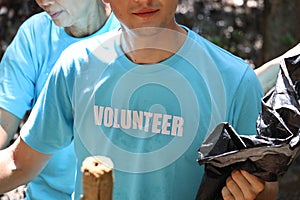 Volunteer in blue t-shirt holding garbage bag, ecology man cleaning and picking up trash to reduce land pollution environmental