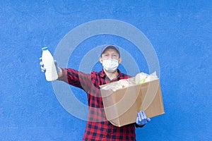 Volunteer with a box of food on a blue background, donations