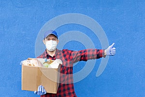 Volunteer with a box of food on a blue background, donations