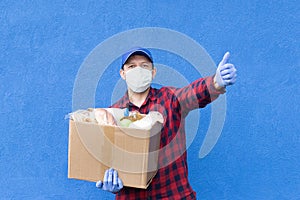 Volunteer with a box of food on a blue background, donations