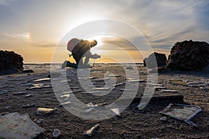 Volunteer cleaning a beach at sunset to preserve environment