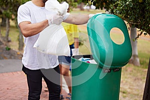 Volunteer cleaning, trash bin and man throw garbage, pollution or waste product for environment support. Community help