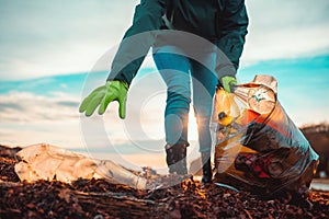 A volunteer collects garbage on a muddy beach. Close-up. The concept of Earth Day. Bottom view