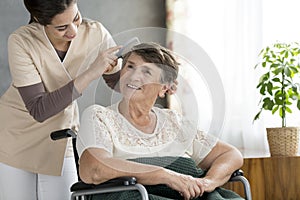 Volunteer combing older patient`s hair