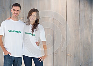 Volunteer couple standing against wooden background